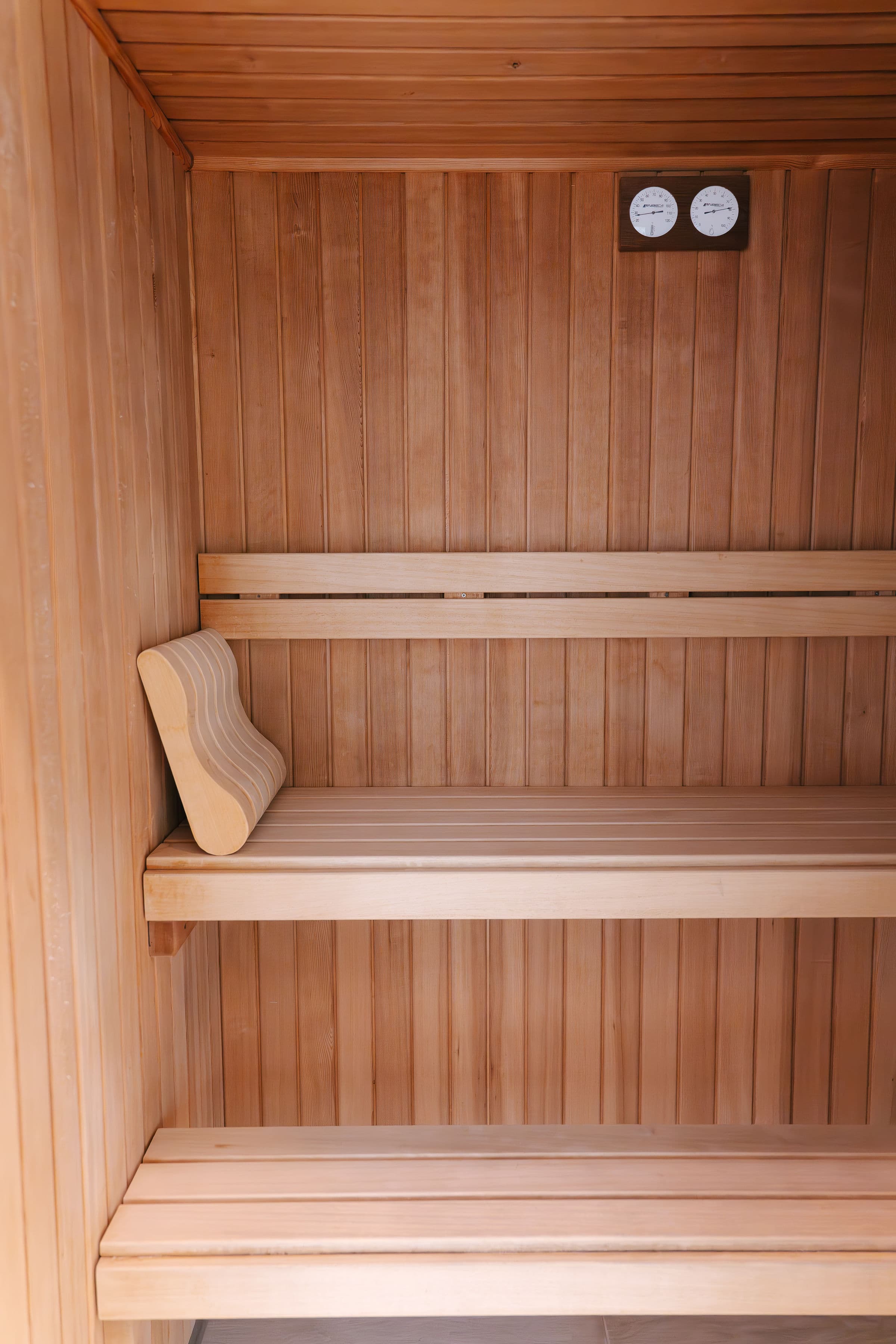 Sauna finlandesa de madera con cubo tradicional y estufa de piedras en el spa
