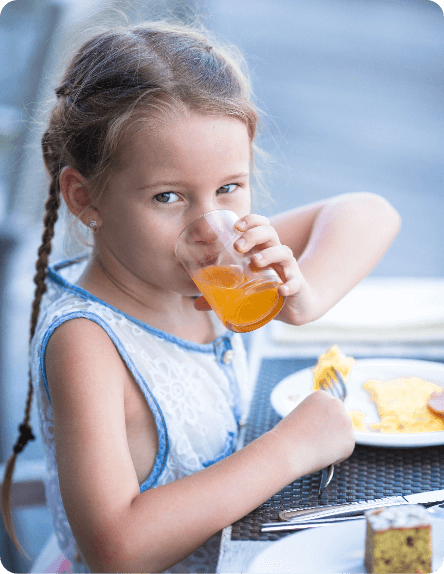Niña bebiendo zumo de naranja en el desayuno en la terraza del hotel de Peñíscola, opciones familiares