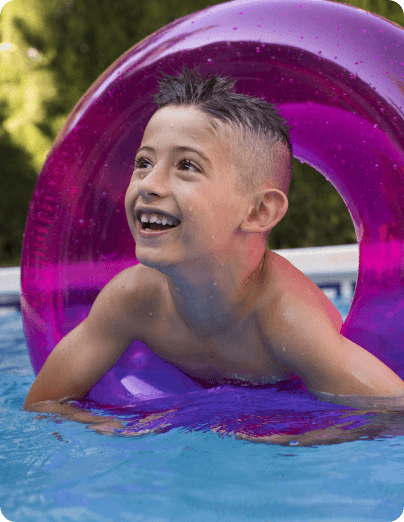 Niño sonriendo con flotador morado en la piscina del hotel de Peñíscola, actividades acuáticas para niños